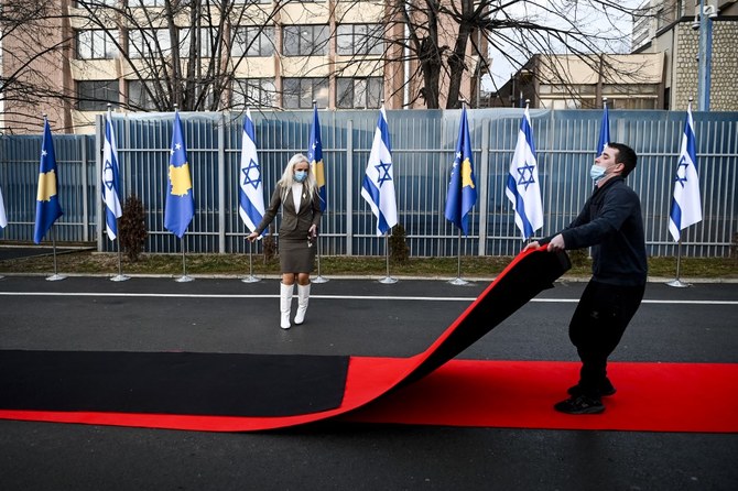 A Kosovo worker drags the red carpet next to Kosovo’s and Israel’s flags displayed during a ceremony at the headquarters of the Foreign Ministry in Pristina on Feb. 1, 2021. (File/AFP)