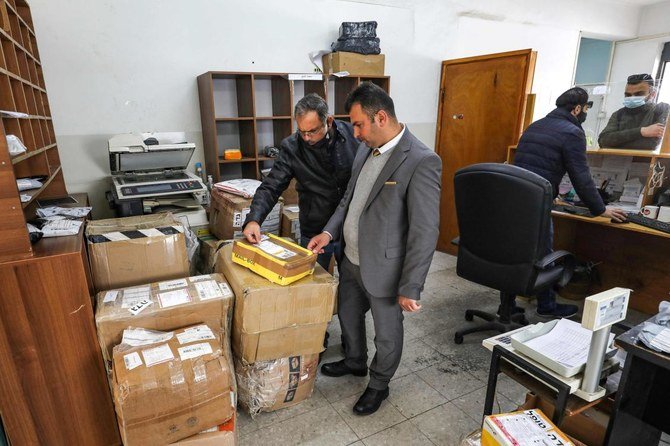 Palestinian postal workers examine a mail package at a post office in the city of al-Bireh, about 15 kilometres north of Jerusalem in the occupied West Bank, on February 7, 2021. (AFP)