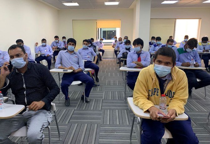 Men wait to be vaccinated against COVID-19 in Dubai on Feb. 8, 2021. Key transport hub Dubai began today mass vaccination of public transport workers, with the Gulf emirate aiming to remain open to international tourism despite surge in cases. (AFP)