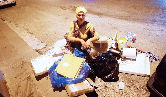 A woman looks for food in a pile of waste late at night in Ankara. (File/AFP)