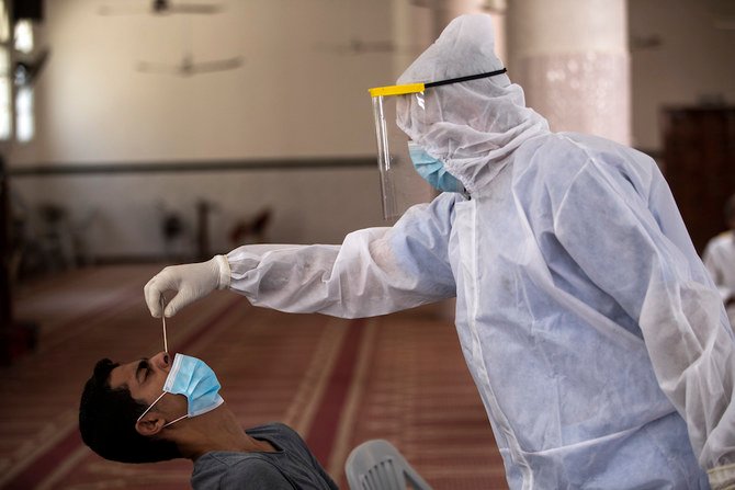 A Palestinian paramedic wearing a full protective suit, takes a nasal swab to test for COVID-19 from a man, at a mosque in Gaza City. (File/AP)