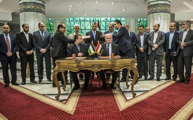 Hamas’ Salah Al-Arouri, left, and Fatah’s Azzam Al-Ahmad sign a reconciliation deal in Cairo on Oct. 12, 2017, as the two rival Palestinian movements moved to end their decade-long split. (AFP)