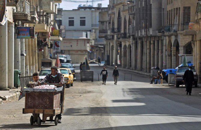An Iraqi vendor pushes his cart along a street in Baghdad on February 19, 2021, as authorities re-imposed partial lockdown measures until early March after detecting a new strain of the coronavirus. (AFP)