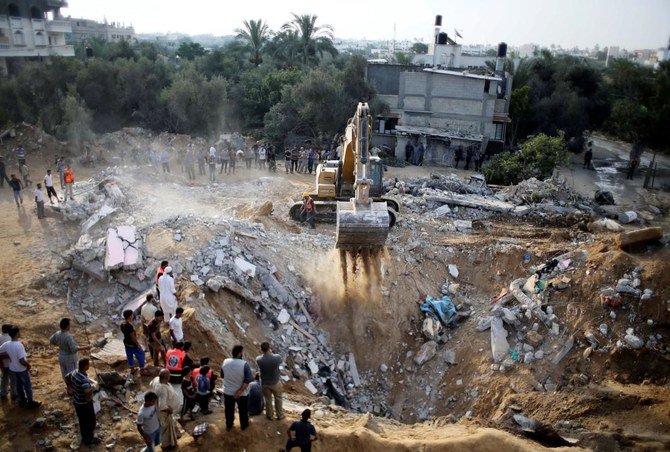 Palestinians gather as an excavator searches for victims amongst the rubble of Abu Jama family's house, in Khan Younis in the southern Gaza Strip July 21, 2014. (Reuters)