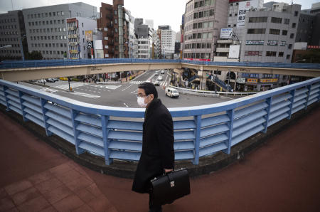 A man wearing a face mask walks on a pedestrian overpass in Tokyo on Thursday, Feb. 18, 2021. (AP)