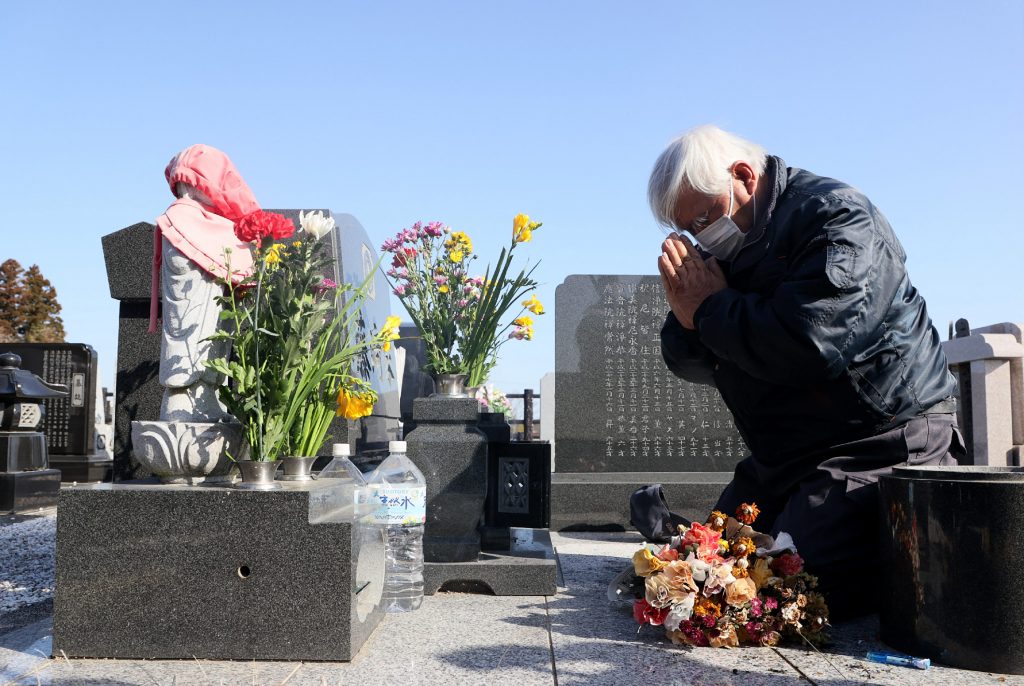 A Local resident who lost his daughter pays a respect at a cemetery in Namie, Fukushima prefecture on March 11, 2021, the 10th anniversary of the 9.0 magnitude earthquake which triggered a tsunami and nuclear disaster. (AFP)