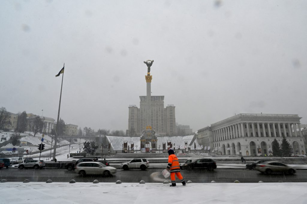A communal worker spreads salt on a sidewalk in the center of the Ukrainian capital of Kiev on March 12, 2021, during an unexpected snowfall and heavy wind following warm spring days. (AFP)