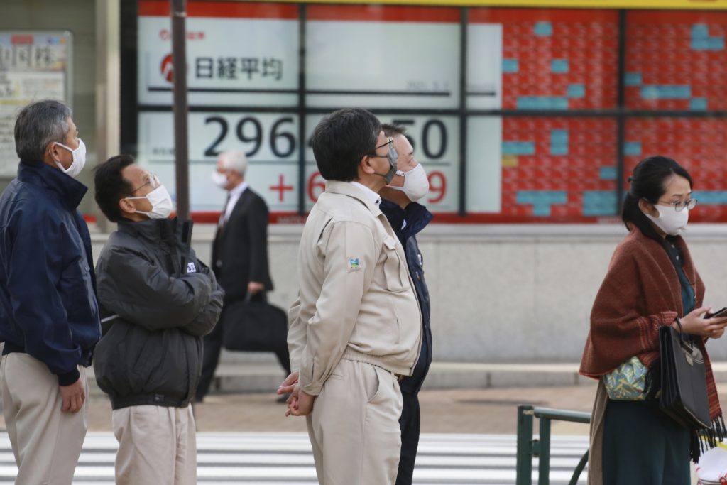 People stand by an electronic stock board of a securities firm in Tokyo, March 1, 2021. (File photo/AP)