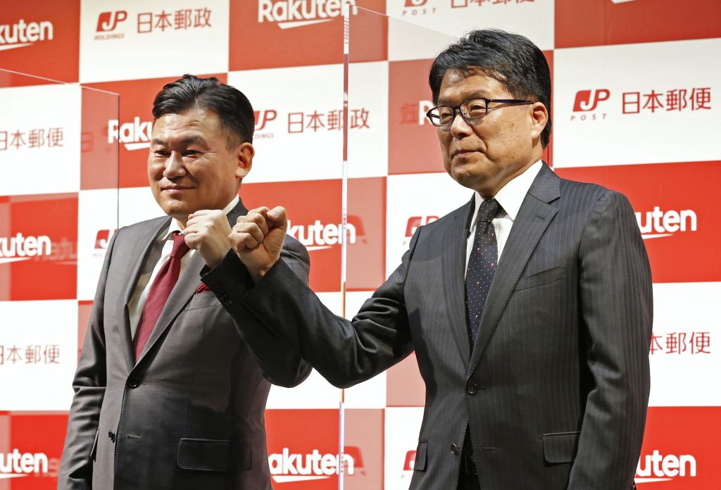 Japan Post Holdings President Hiroya Masuda, right, and Rakuten President Hiroshi Mikitani, left, pose together during a press conference on their strategic partnership on Dec. 24, 2020 in Tokyo. (Sadayuki Goto/Kyodo News via AP)