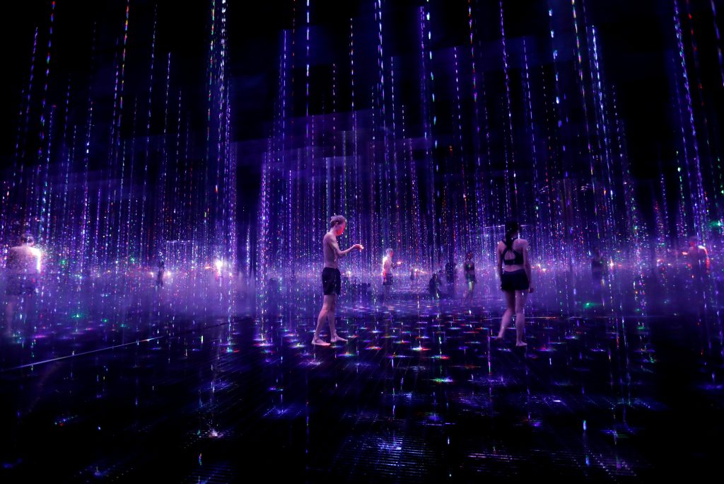 Staffs of teamLab wearing swimming suits walk inside digital artwork combined with light, water and sound during a demonstration of TikTok teamLab Reconnect, digital artwork combined with sauna, ahead of its opening to the public this month in Tokyo, Japan, March 13, 2021. (Reuters)