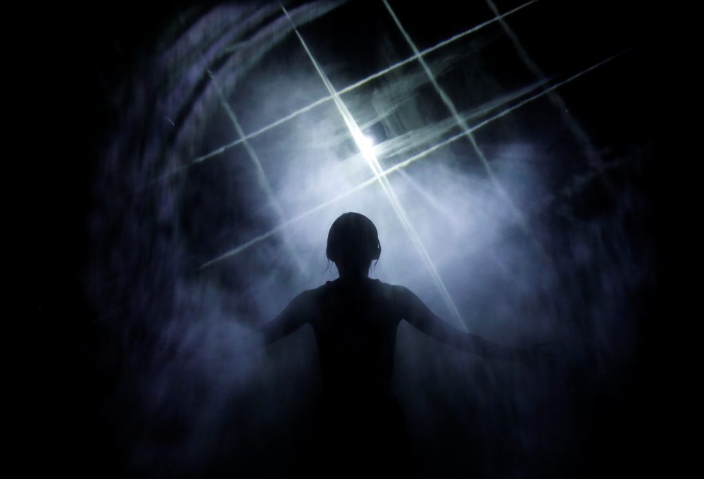 A staff of teamLab wearing a swimming suit stands inside a digital artwork combined with light, mist and sound during a demonstration of TikTok teamLab Reconnect, digital artwork combined with sauna, ahead of its opening to the public this month in Tokyo, Japan, March 13, 2021. (Reuters)