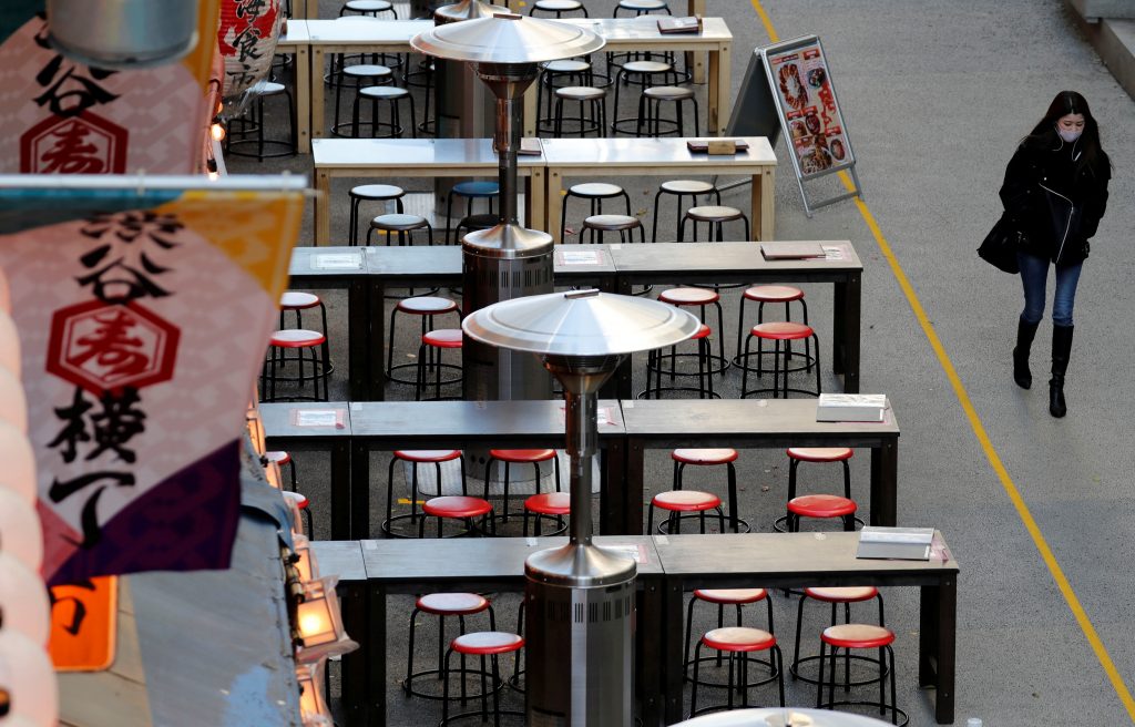  A woman, wearing a protective mask against COVID-19, walks past empty tables at a restaurant at Shibuya in Tokyo, Japan, January 7, 2021. (REUTERS)