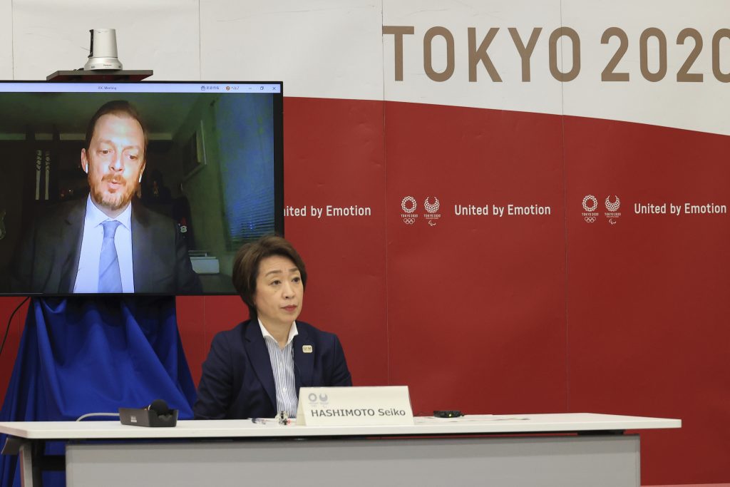 International Paralympic Committee (IOC) President Andrew Parsons, on a screen, delivers an opening speech while Tokyo 2020 Organizing Committee president Seiko Hashimoto listens at a five-party meeting of Tokyo 2020 Olympic and Paralympic Games with International Olympic Committee (IOC) President Thomas Bach, Tokyo Gov. Yuriko Koike and Japanese Olympic Minister Tamayo Marukawa in Tokyo Saturday, March 20, 2021. (Yoshikazu Tsuno/Pool Photo via AP)