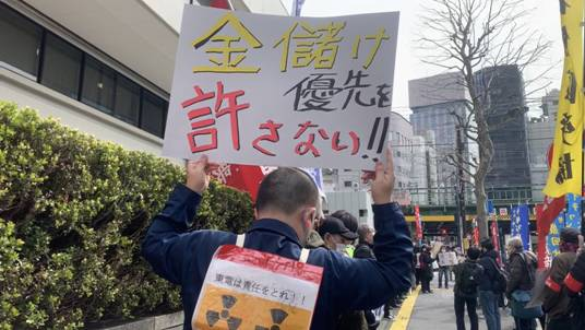 A protester carries a banner saying “We won’t forgive those who put money making as priority” at the sidewalk of TEPCO in Tokyo. (ANJ Photo)