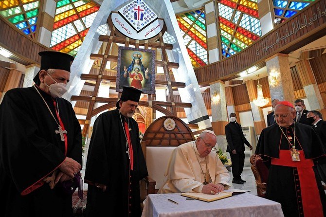 Pope Francis signs the guest book at the Syriac Catholic Cathedral of Our Lady of Salvation in Baghdad on March 5, 2021. (AFP)