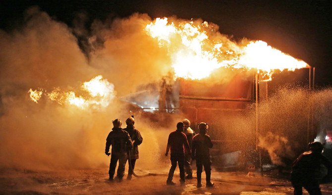 Members of the Syrian Civil Defense (White Helmets) extinguish a fire which reportedly erupted after a bombardment from unknown sources of makeshift oil refining installations in Aleppo province, on March 5, 2021. (AFP)