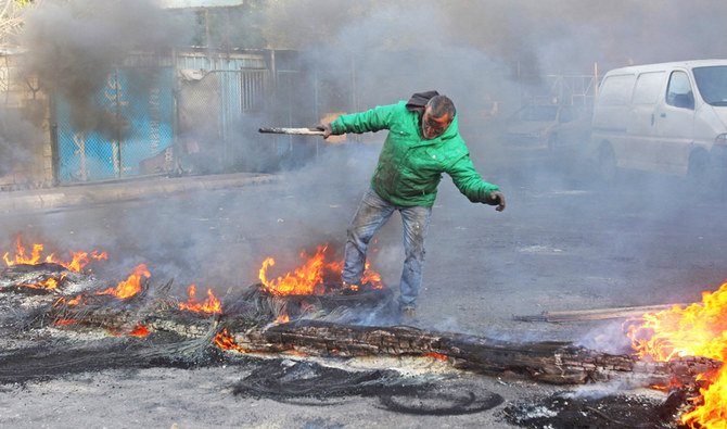 A Lebanese protester sets up a burning barricade to block a road in the southern Lebanese city of Sidon on Wednesday over a deepening economic crisis. (File/AFP)
