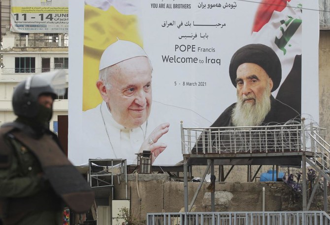 An Iraqi security guard stands in front of a huge billboard bearing portraits of Pope Francis and Grand Ayatollah Ali Sistani (R) in central Baghdad on March 4, 2021, on the eve of the pontiff's first visit to Iraq. (AFP)