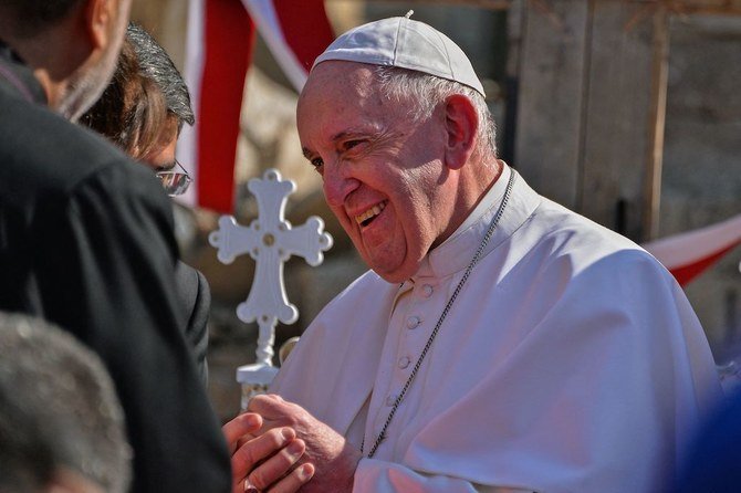 Pope Francis is greeted by people on the podium at the square near the ruins of the al-Tahira-l-Kubra church, in Mosul on March 7, 2021. (AFP)