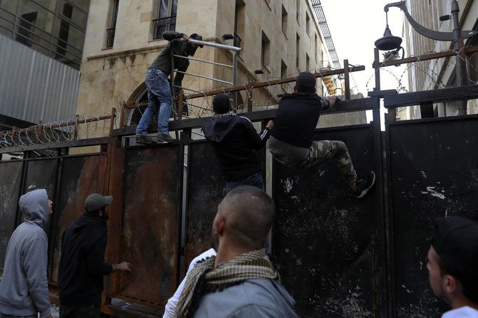 Anti-government protesters climb a metal wall installed by security forces to prevent protesters from reaching the Parliament building, during a protest in Beirut, Lebanon, Saturday, March. 13, 2021. (AP)