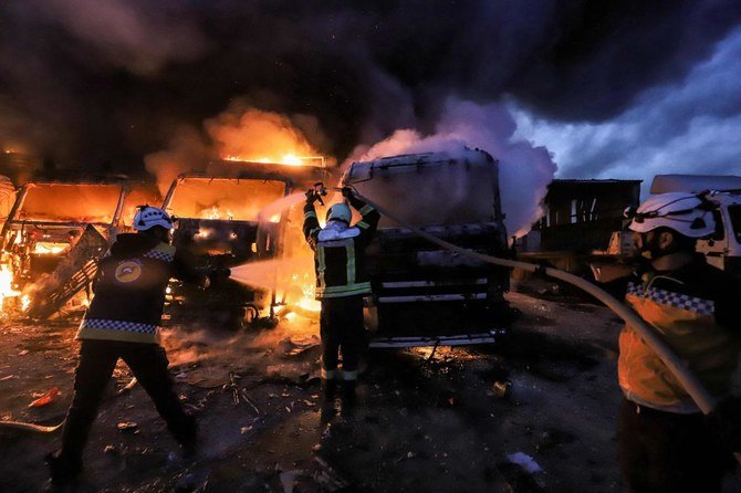 Members of the Syrian civil defence try to put out several trucks and freight vehicles on fire in the aftermath of air strikes at a depot near the Bab al-Hawa border crossing between Syria and Turkey in Syria's rebel-held northwestern Idlib province. (AFP)