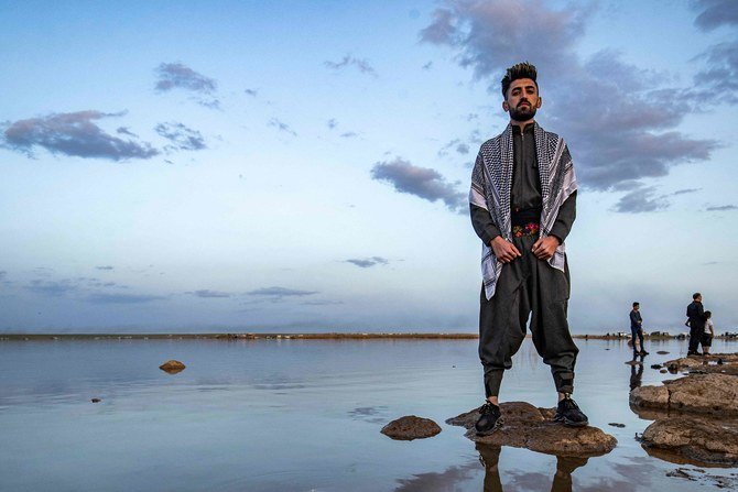 A man stands on a rock in the Mazqaft water reservoir near Qahtaniyah, in Syria’s northeastern Hasakah province, during Syrian Kurdish Nowruz, Persian New Year, celebrations, Mar. 21, 2021. (AFP)