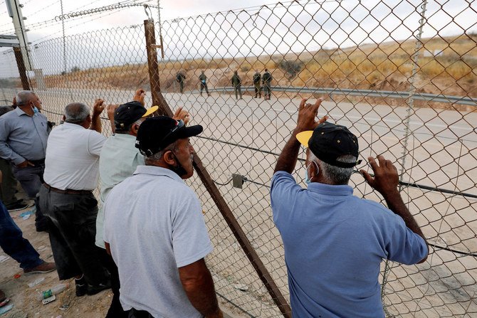 Palestinian laborers, who were not able to cross into Israel for work, stand by a fence near an Israeli checkpoint that was closed near Hebron in the Israeli-occupied West Bank. (File/Reuters)