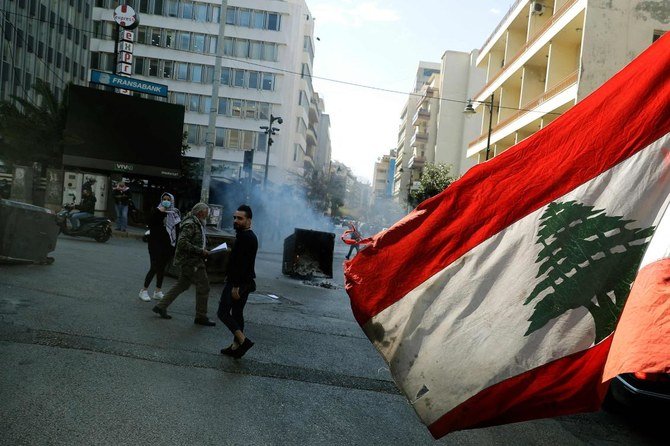 An anti-government demonstrator blocks the street with burning garbage dumpsters in front of Lebanon's central bank in the capital Beirut on March 16, 2021. (AFP)