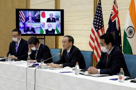 Japan's Prime Minister Yoshihide Suga (second right) speaks next to a monitor displaying the virtual meeting of US President Joe Biden (top left), Australia's Prime Minister Scott Morrison (bottom left) and India's Prime Minister Narendra Modi during the virtual Quadrilateral Security Dialogue (Quad) meeting, at his official residence in Tokyo on March 12, 2021. (AFP)