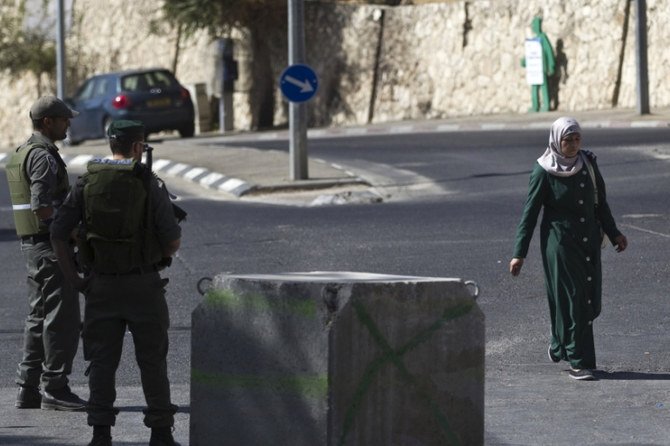 A Palestinian woman walks past Israeli paramilitary border police at a roadblock in East Jerusalem. (Reuters)