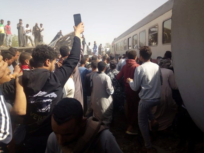 People gather around the wreckage of two trains that collided in the Tahta district of Sohag province on March 26, 2021. (AFP)