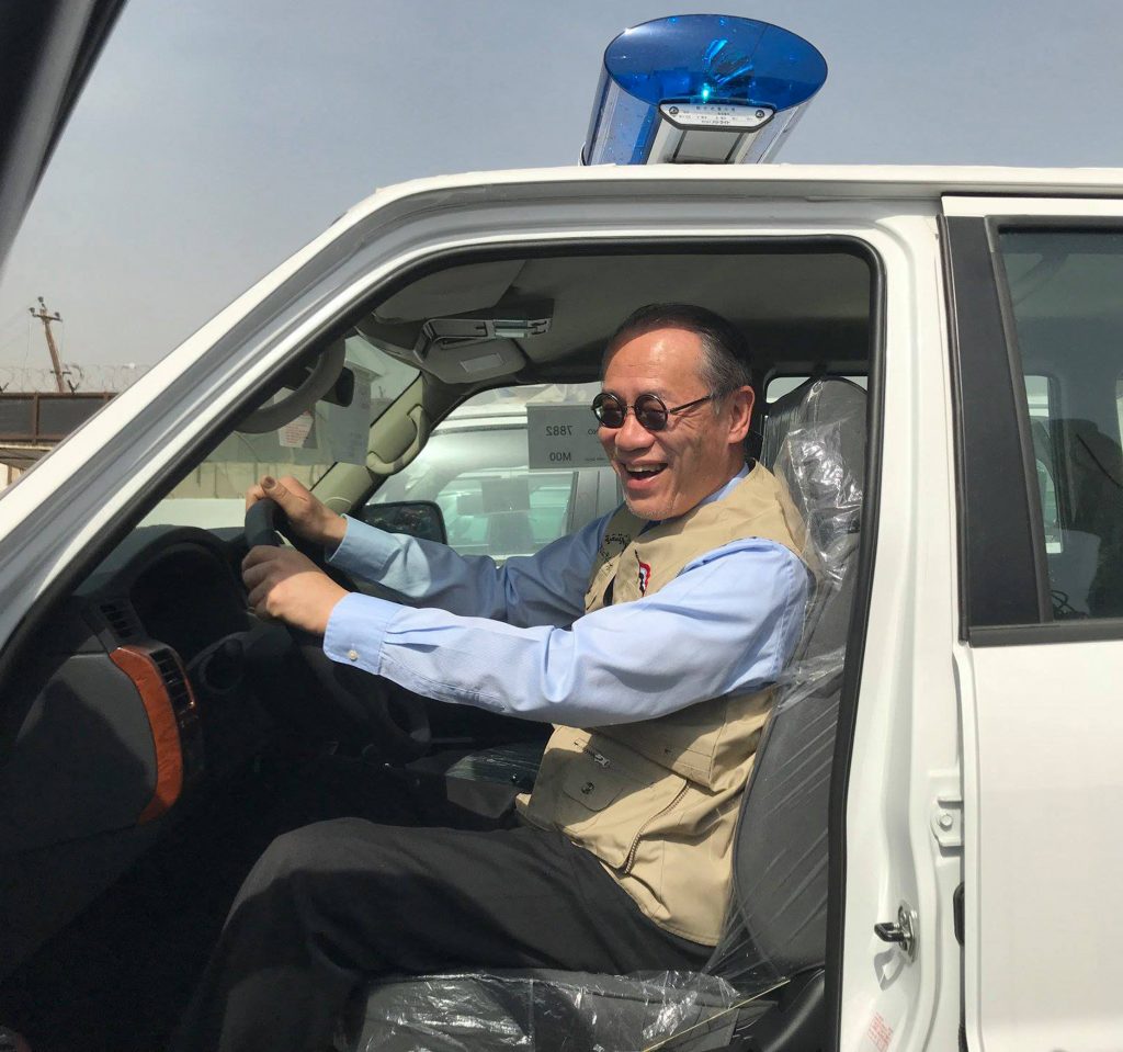 A handout picture released by the official Facebook page of the Embassy of Japan in Iraq on March 21, 2018 shows Japanese Ambassador Fumio Iwai riding in a pick-up truck during a handover ceremony of vehicles provided by Japan to the Iraqi police at an unspecified location in Iraq.  (AFP)