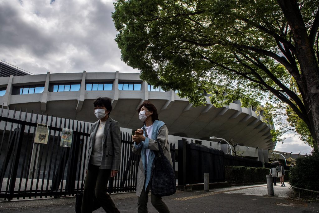 Pedestrians walk outside a closed gate of the Yoyogi National Stadium, a venue for Tokyo 2020 Olympic and Paralympic Games, in Tokyo on April 3, 2021. (AFP)