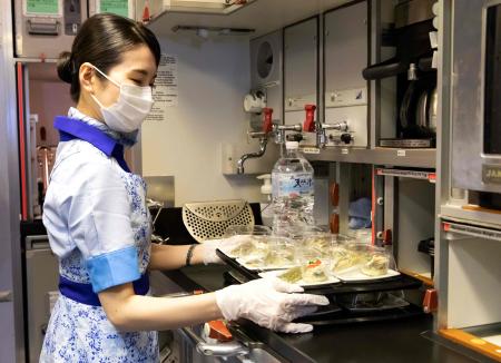 In this handout photograph taken on March 31, 2021 by All Nippon Airways (ANA), a flight attendant prepares food for customers on a parked plane at Haneda airport in Tokyo. (AFP)