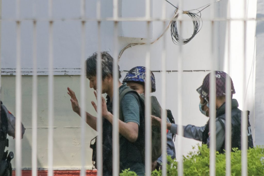 Japanese journalist Yuki Kitazumi raises his hands as he is escorted by police upon arrival at the Myaynigone police station in Sanchaung township in Yangon, Myanmar. (File photo/AP)