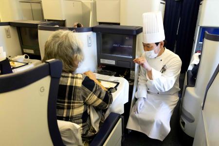 In this handout photograph taken on March 31, 2021 by All Nippon Airways (ANA), a chef speaks with a customer on a parked plane at Haneda airport in Tokyo. (AFP)