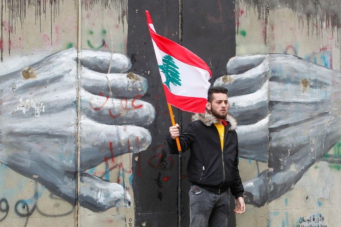 A man holds a Lebanese flag as demonstrators gather during a protest over the deteriorating economic situation, in Beirut, Lebanon April 10, 2021. (Reuters)
