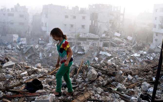 A Palestinian girl walks on the rubble-strewn ceiling of her family’s home in Gaza City, in 2014. (AFP)