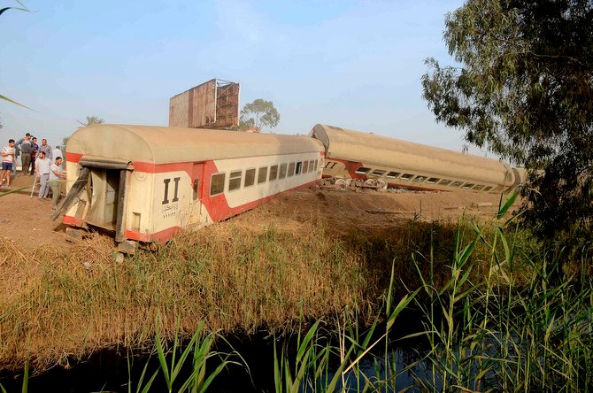 People gather at the site where a passenger train derailed injuring at least 100 people, near Banha, Qalyubia province, Egypt, Sunday, April 18, 2021. (AP)