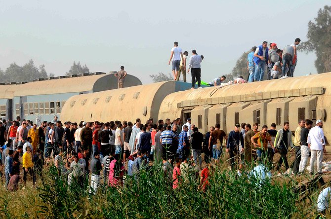 People gather at the site where a passenger train derailed injuring at least 100 people, near Banha, Qalyubia province, Egypt, Sunday, April 18, 2021. (AP)