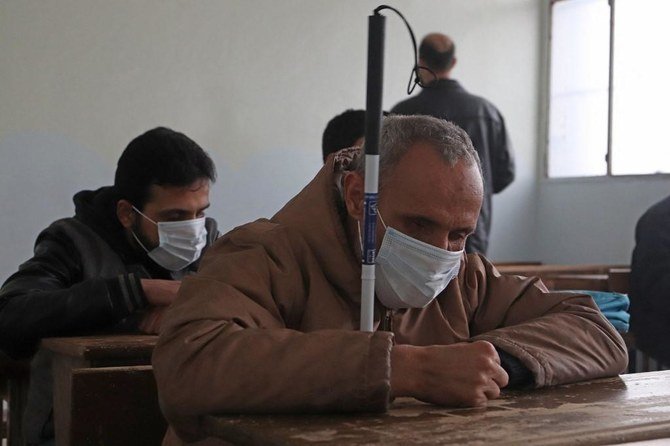 Visually impaired Syrian men, wearing protective masks due to the COVID-19 pandemic, attend a lesson at a school for the blind in the northwestern city of Idlib on Dec. 20, 2020. (File/AFP)
