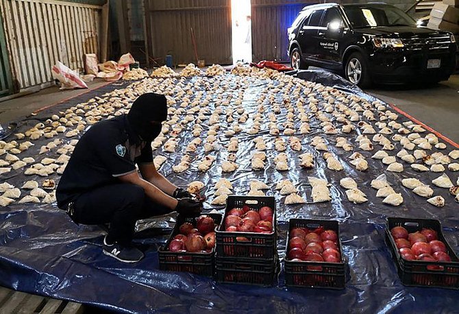 A Saudi custom officer opens imported pomegranates, as customs foiled a attempt to smuggle millions of Captagon pills, which came from Lebanon, at Jeddah Islamic Port on April 23, 2021. (SPA)
