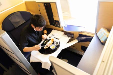 In this handout photograph taken on March 31, 2021 by All Nippon Airways (ANA), a customer has his meal on a parked plane at Haneda airport in Tokyo. (AFP)
