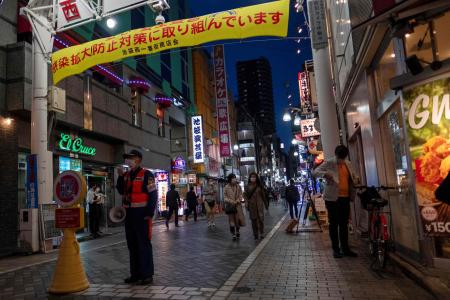 A security guard stands at an entrance of a restaurant and bar area in Tokyo on April 26, 2021, during a new coronavirus state of emergency covering the Tokyo, Osaka, Kyoto and Hyogo regions. JIJI Press