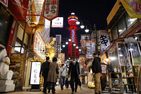 Pedestrians wearing protective face masks, amid the coronavirus disease (COVID-19) pandemic, are seen in front of the Tsutenkaku Tower in Osaka, Japan in this photo taken by Kyodo April 7, 2021. (Reuters)