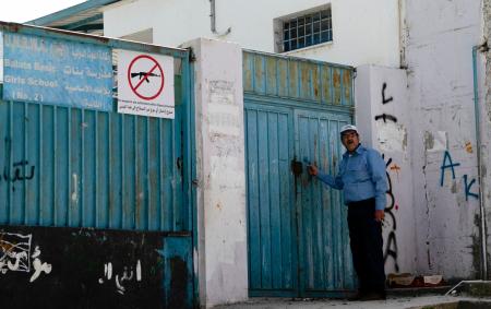 A Palestinian man stands at the entrance of a school run by the United Nations Relief and Works Agency for Palestine Refugees (UNRWA) in Balata refugee camp east of Nablus in the occupied West Bank, on April 8, 2021. (AFP)