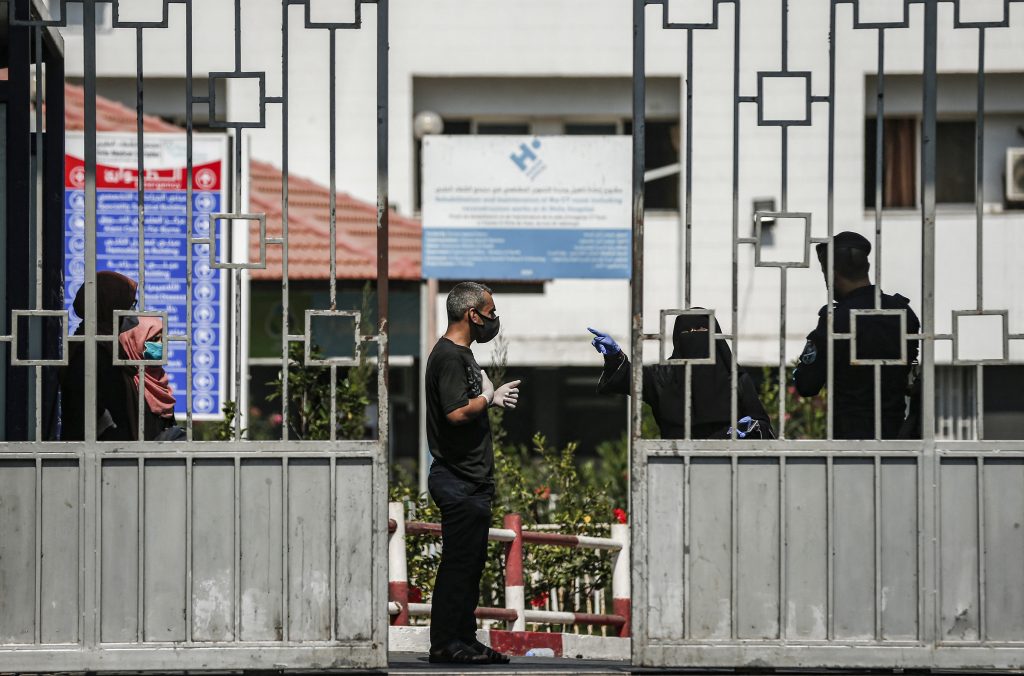 A man and woman, mask-clad due to the COVID-19 coronavirus pandemic, speak to security forces loyal to Hamas at the gate of al-Shifa hospital at al-Shati camp for Palestinian refugees in Gaza City on August 29, 2020. (AFP)