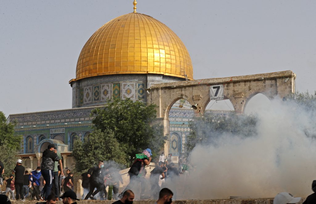 Palestinian protesters run for cover amid clashes with Israeli security forces at Jerusalem's Al-Aqsa mosque compound on May 10, 2021. (AFP)