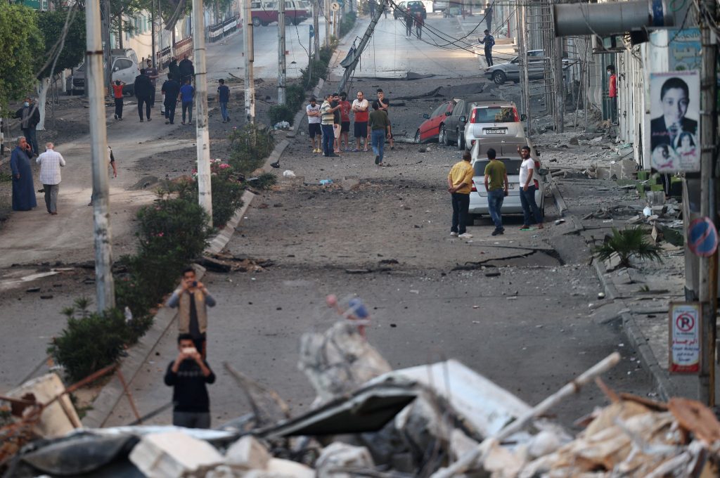 Palestinian men are pictured outdoors in a heavily-damaged residential neighbourhood of Gaza City early on May 16, 2021, following massive Israeli bombardment of the Hamas-controlled enclave. (AFP)