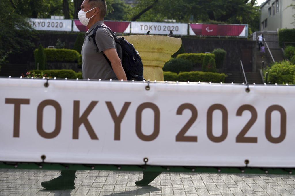 A man wearing a mask to help protect against the spread of the coronavirus walk near banners to promote the Tokyo Olympic Games Tuesday, May 25, 2021, in Tokyo. (AP Photo/Eugene Hoshiko)